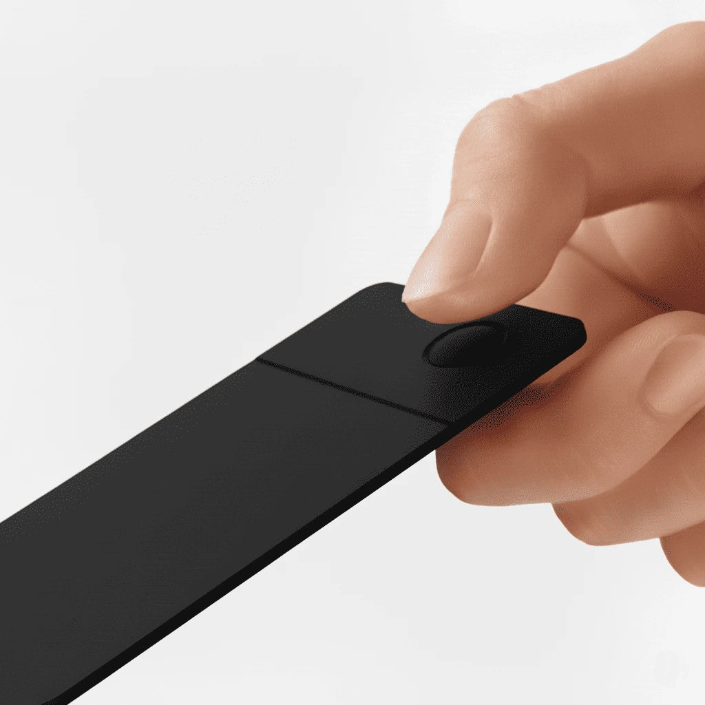 A hand holding a sleek black tracking card with a circular button. The setting is minimalistic, highlighting the device's modern, compact design.