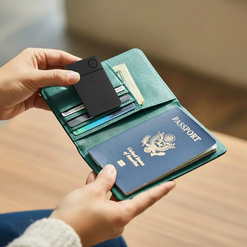 Hands hold an open turquoise passport holder containing a U.S. passport, several credit cards, and a black tracking card. Warm, relaxed setting.